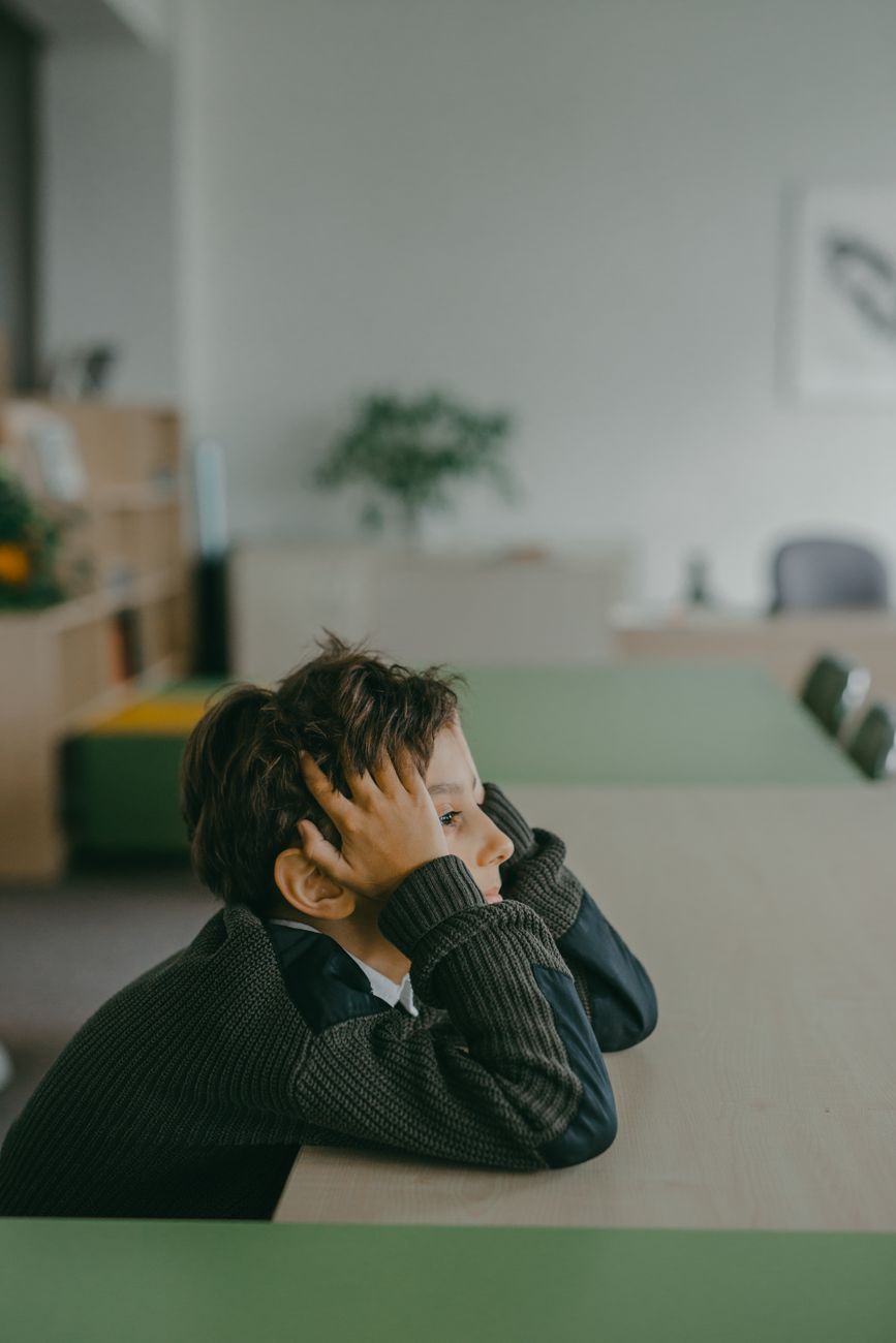a boy in a sweater leaning on a table